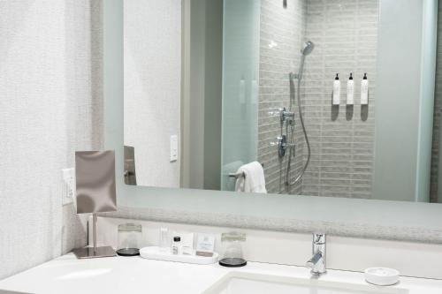 a bathroom with a sink and a mirror and a shower at Maui Coast Hotel in Kihei