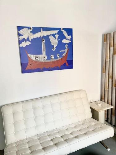 a white couch in a room with a picture of a boat at Cyclops House in Serifos Chora