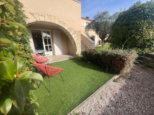 a red chair sitting on a lawn in front of a house at Logis Hôtel Restaurant La Bergerie in Aragon