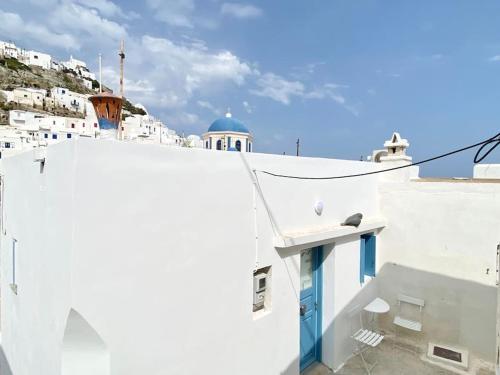 a white building with a blue door on a hill at Cyclops House in Serifos Chora
