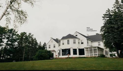 a large white house with a porch on a lawn at Island Estate in La Pointe