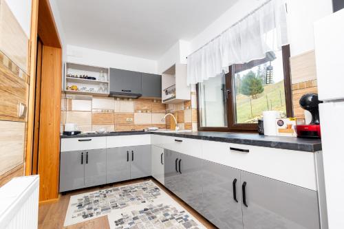 a kitchen with white cabinets and a window at Cabana la Piatră in Pojorîta