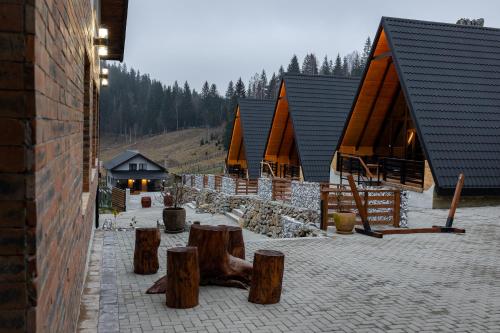 a group of lodges with some logs and buildings at Cabana la Piatră in Pojorîta