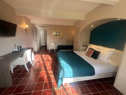 a hotel room with a large bed and a desk at Logis Hôtel Restaurant La Bergerie in Aragon