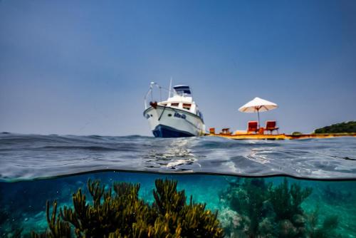 a boat in the ocean next to a reef at Turtle Inn by Francis Ford Coppola in Placencia Village