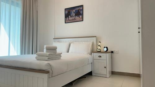 a white bedroom with a bed with towels on it at Sleek 1BR in DSO, Dubai in Dubai