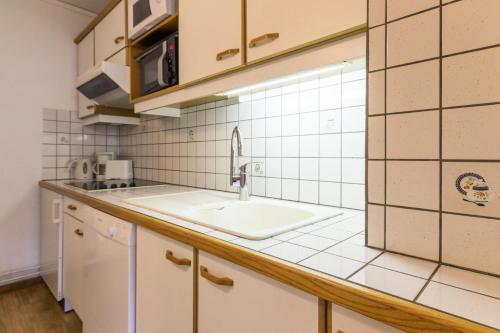 Il comprend une cuisine avec un évier et un mur carrelé blanc. dans l'établissement Résidence Vercors - Appartement 7 personnes - Plagne Centre MAE-4474, à La Plagne Tarentaise