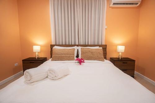 a bedroom with a white bed with towels and two lamps at Arashi Beachfront - The best sunsets in Aruba! in Madiki