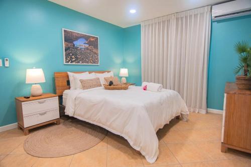 a bedroom with a large bed and a blue wall at Arashi Beachfront - The best sunsets in Aruba! in Madiki