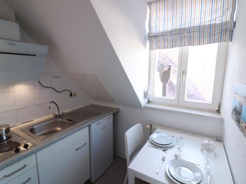 a small white kitchen with a sink and a window at Ahlbeck, Schloss Hohenzollern Fewo Schlosszimmerchen in Ahlbeck