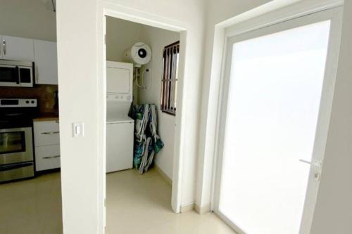 a white kitchen with a door leading into a room at Aruba Breeze Condo A5 in Palm-Eagle Beach