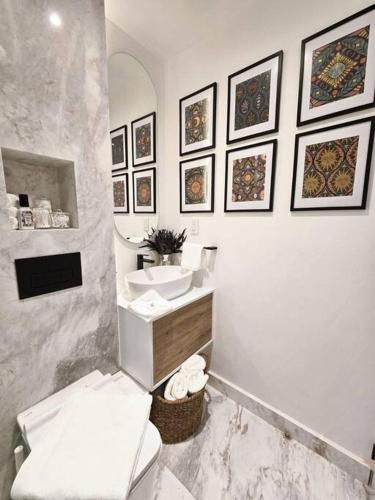 a bathroom with a toilet and a sink and pictures on the wall at Ultimate Getaway in Luxe Studio in Mexico City