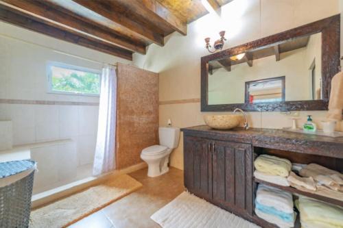 Un baño con lavabo, inodoro y espejo. en Casa Luna Entire Home, en Palm-Eagle Beach