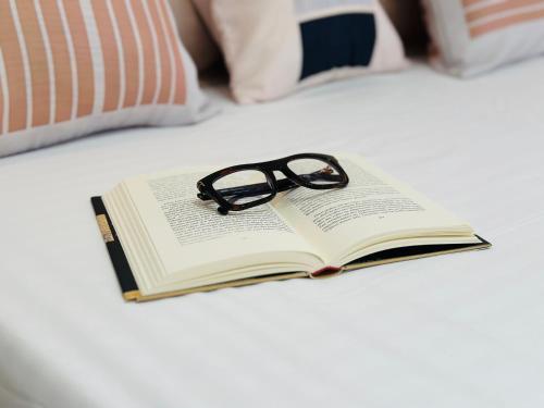 a book with a pair of glasses sitting on a bed at BATUU Luxury Living in Bizerte
