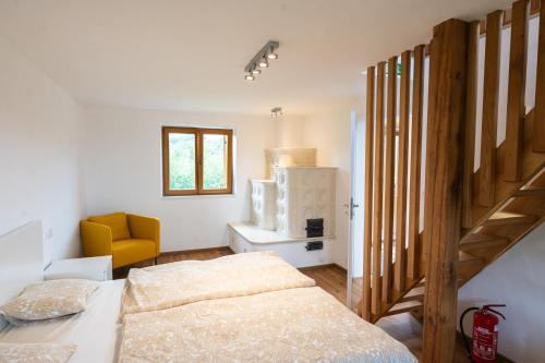 a bedroom with a bed and a staircase with a yellow chair at Zidanica sredi dolenjskih gričev - V gaj in Trebnje
