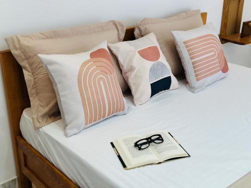 a bed with pillows and a book and glasses on it at BATUU Luxury Living in Bizerte