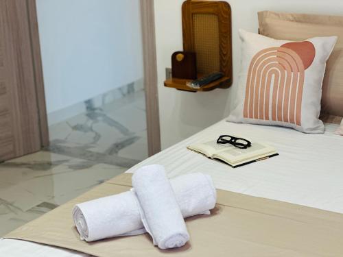 a bed with two rolled towels and a book on it at BATUU Luxury Living in Bizerte