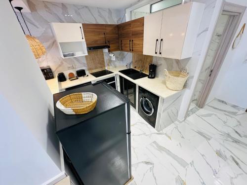 a small kitchen with white cabinets and a black refrigerator at BATUU Luxury Living in Bizerte