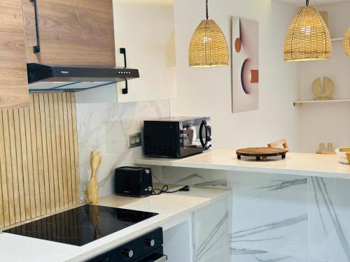 a kitchen with white counters and a sink and a microwave at BATUU Luxury Living in Bizerte
