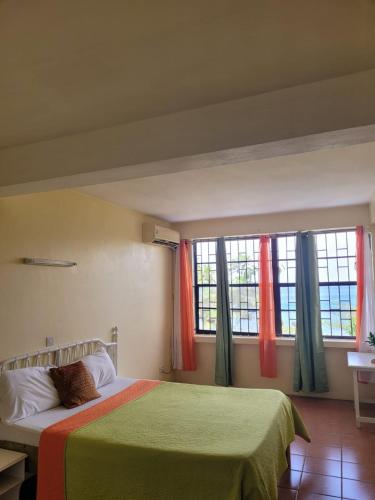 a bedroom with a bed with green sheets and windows at Casa del Vega a Little Peace of Heaven in Castries