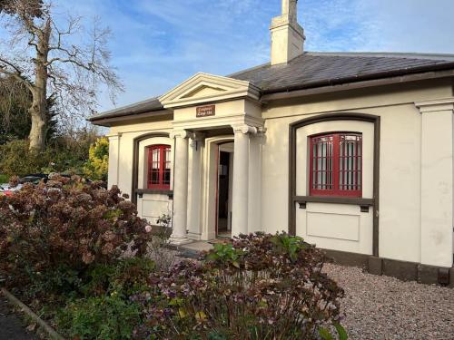 a small white house with red windows at The Lyttle Cottage in Belfast