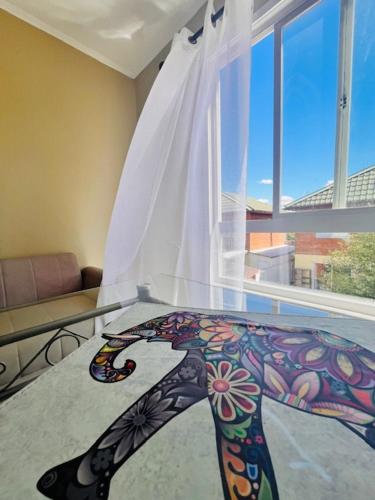 a room with a glass table with a painting on the floor at Hostal Hostal in Los Ángeles