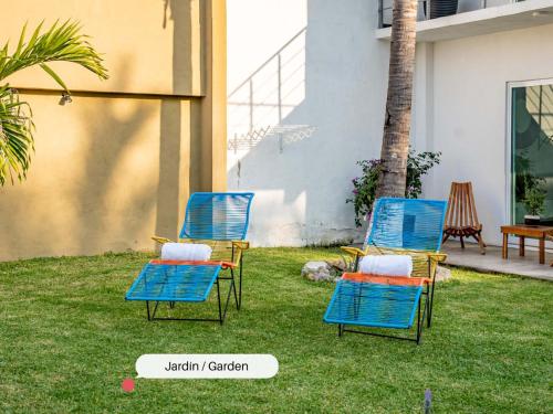 two blue chairs sitting on the grass in a yard at Vida Casa Kuxtal Rooftop con vista al Lago in Vista Hermosa