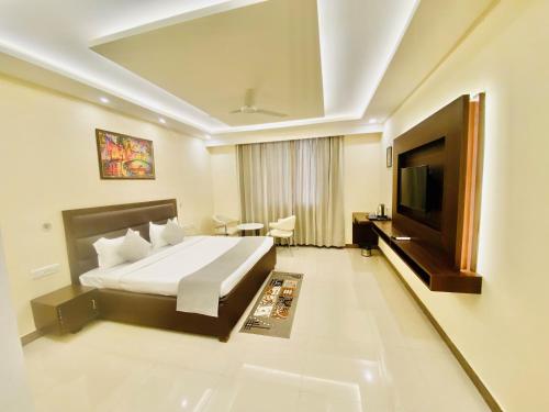 a hotel room with a bed and a flat screen tv at Ayansh Klyde Inn, Lucknow in Lucknow