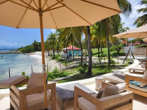 a beach with chairs and an umbrella and the ocean at Studio Indigo Pierre et Vacances in Sainte-Anne