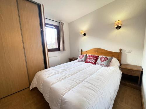 une chambre avec un grand lit blanc avec des oreillers rouges dans l'établissement Les Chalets Des Evettes - Appartement cozy au pied des pistes dans une résidence avec piscine MAE-6431, à Flumet