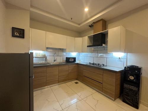 a kitchen with white cabinets and a black refrigerator at *Designer’s Luxurious 1BHK at Top Location of Twin Cities!! in Rawalpindi