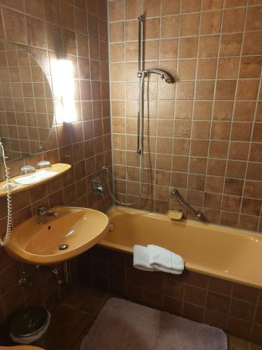 a bathroom with a sink and a tub and a mirror at Goldner Engel, Restaurant - Hotel - Metzgerei in Laudenbach