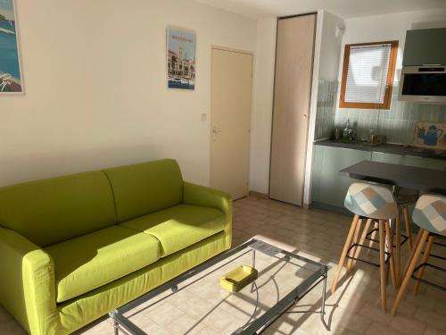 un salon avec un canapé vert et une table dans l'établissement Appartement T2 avec piscine, à Sanary-sur-Mer
