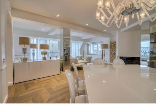 une cuisine et une salle à manger avec une table et des chaises blanches dans l'établissement Palais Privé Luxe Vue Tour Eiffel Confort Exclusif, à Paris