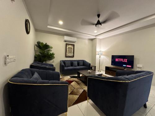 a living room with blue couches and a tv at *Designer’s Luxurious 1BHK at Top Location of Twin Cities!! in Rawalpindi