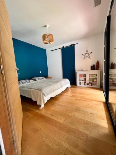 - une chambre avec un lit aux murs bleus et du parquet dans l'établissement Maison en bois au calme, 10 min Montauban, à Corbarieu