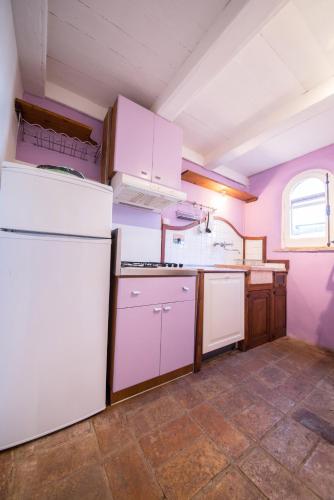 a kitchen with white appliances and a pink wall at Da Bacchetta in Assisi