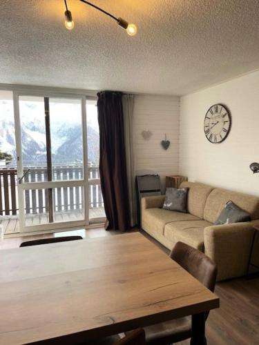 un salon avec un canapé et une horloge au mur dans l'établissement Résidence Panoramic B - studio cabine 4 personnes MAE-7371, à Orcières