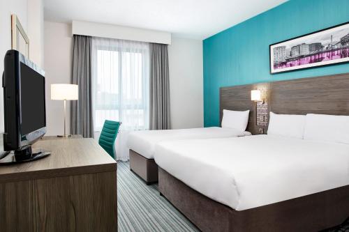 a hotel room with two beds and a flat screen tv at Leonardo Hotel Plymouth in Plymouth