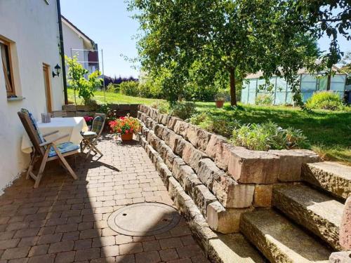 a patio with a table and chairs and a stone wall at "Gemütliches HomeAway" - Dein Zuhause in der Ferne in Kirchberg an der Jagst