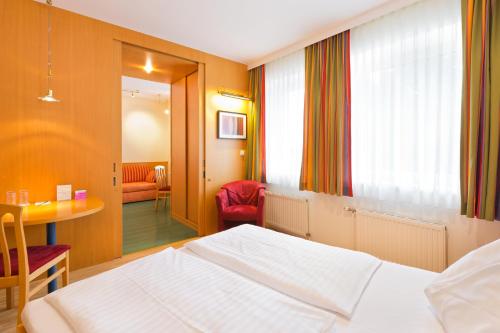 a bedroom with a white bed and a table and chair at Motel Baden in Baden