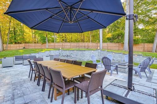 a wooden table and chairs with a blue umbrella at 2 Mi to Six Flags Lake George Home with Large Patio in Queensbury