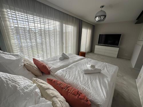 a bedroom with a white bed with pillows and a tv at DOM LIVING - LuxusHaus in Fulda