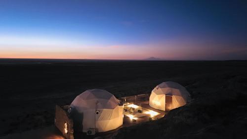 two domes in the middle of a field at sunset at Hotel de Sal Luna Salada in Colchani