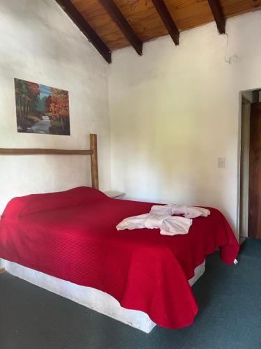 a bedroom with a red bed with towels on it at Sauce Viejo in Mina Clavero