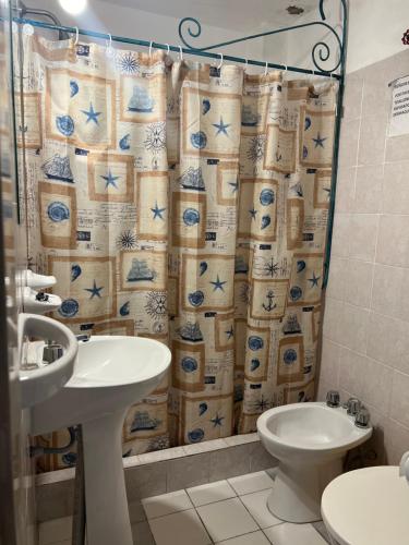 a bathroom with a shower curtain with a toilet and a sink at Sauce Viejo in Mina Clavero