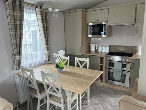 a kitchen with a wooden table and chairs in a kitchen at Firecrest Cove Thornwick Bay, Flamborough in Flamborough