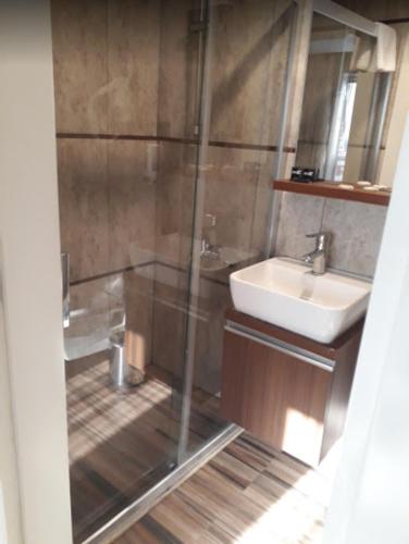 a bathroom with a glass shower and a sink at Hotel Iz in Izmir