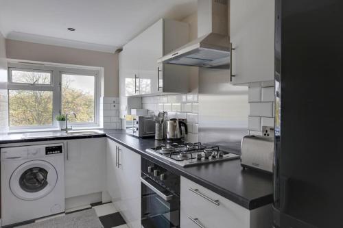 a kitchen with a stove and a washer and dryer at Homely Apartment in Harlow in Great Parndon