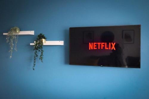 a blue wall with a sign that reads netflix at Homely Apartment in Harlow in Great Parndon